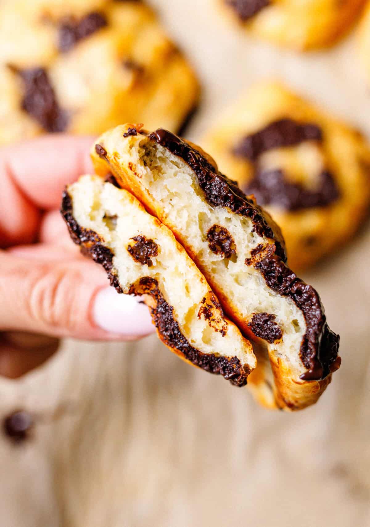Hand holding a cottage cheese scone split open to show the soft interior and melted chocolate