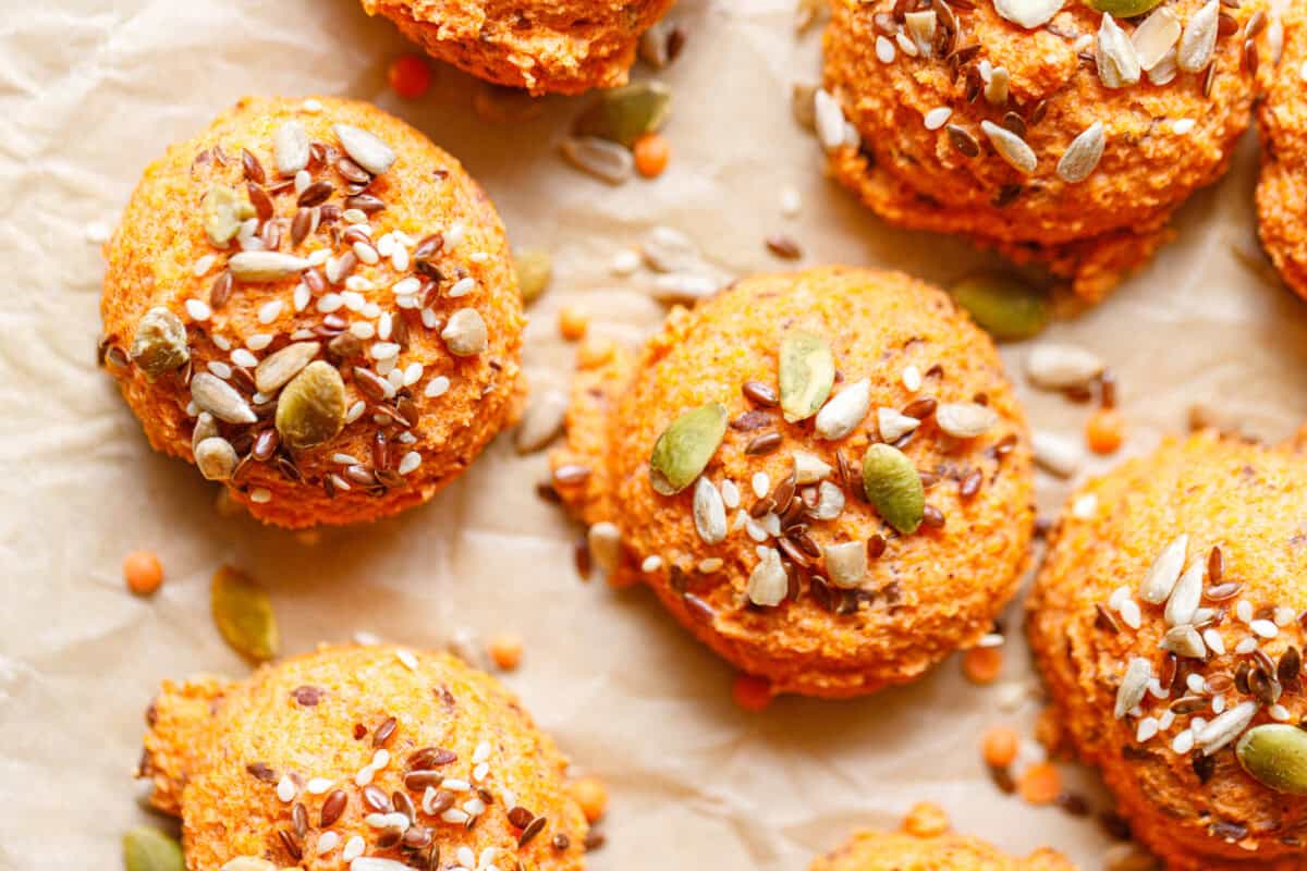 Lentil bread recipe rolls spread on parchment paper with whole red lentils scattered around