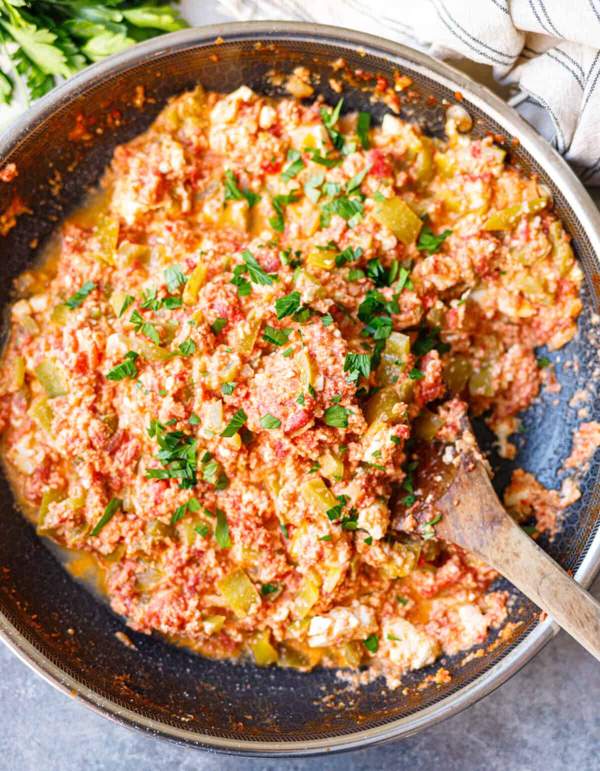 Finished Bulgarian mish mash in a skillet with eggs, feta and chopped parsley on top