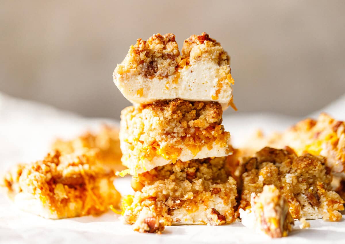 Stack of three low-carb pumpkin crumble bars showing the creamy skyr base, grated pumpkin layer and almond flour crumble topping