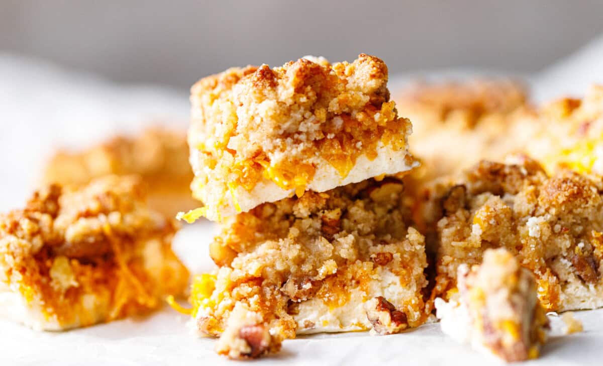 Two pumpkin crumb bars stacked on parchment, with shredded pumpkin and pecans between the skyr base and almond flour crumble
Title: Pumpkin Crumb Bars With Pecans