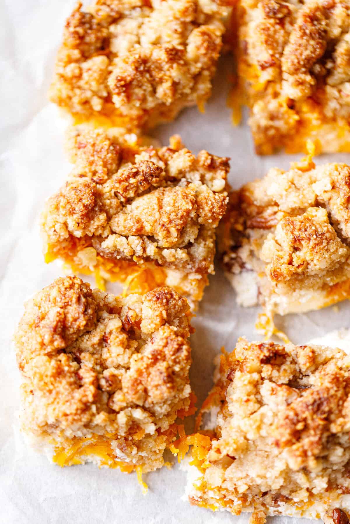 Overhead view of healthy pumpkin bars cut into squares, with golden crumble tops and grated pumpkin peeking out