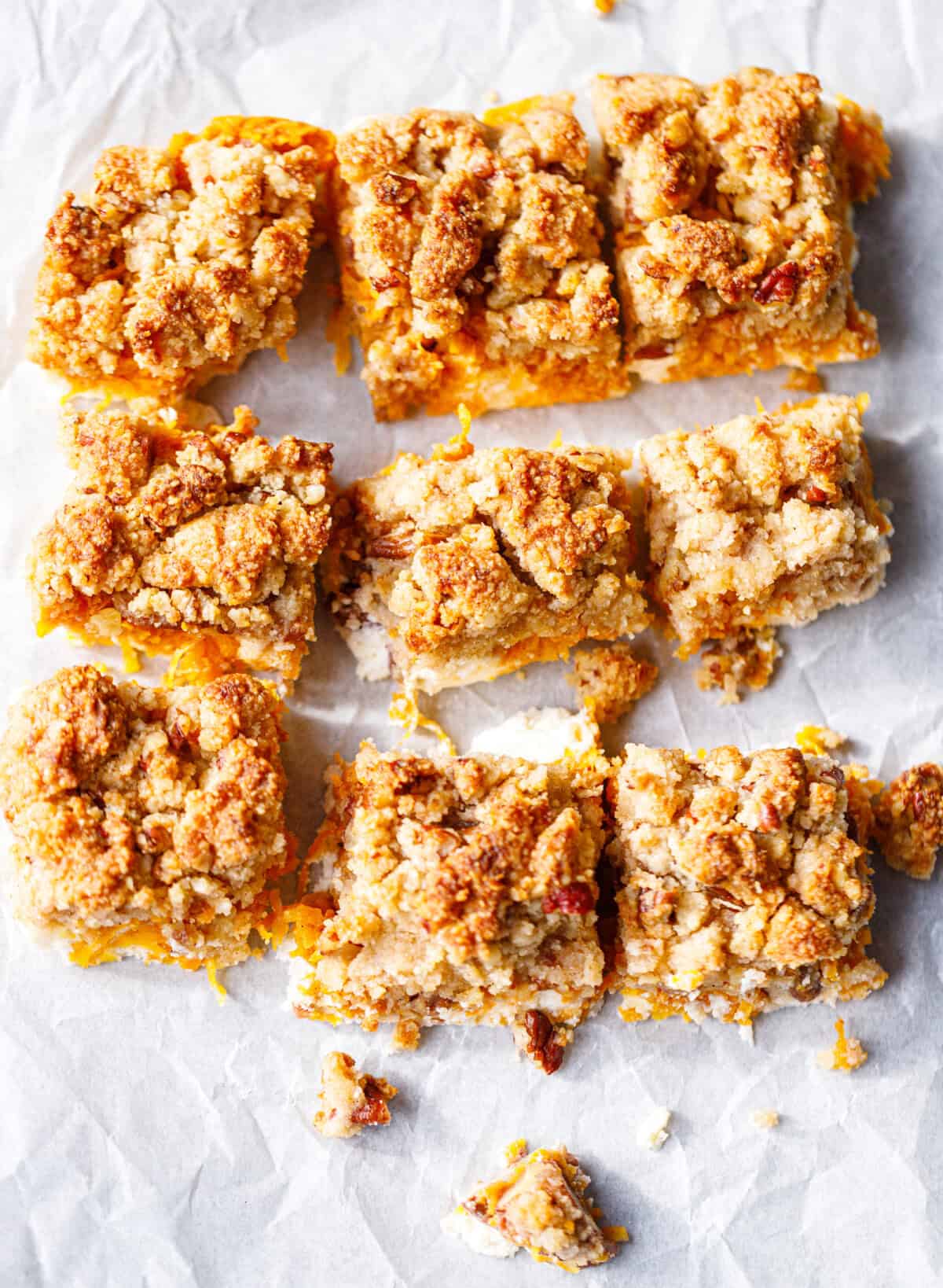 Nine gluten-free pumpkin crumble bars cut and arranged on parchment, made with no crust and no added sugar