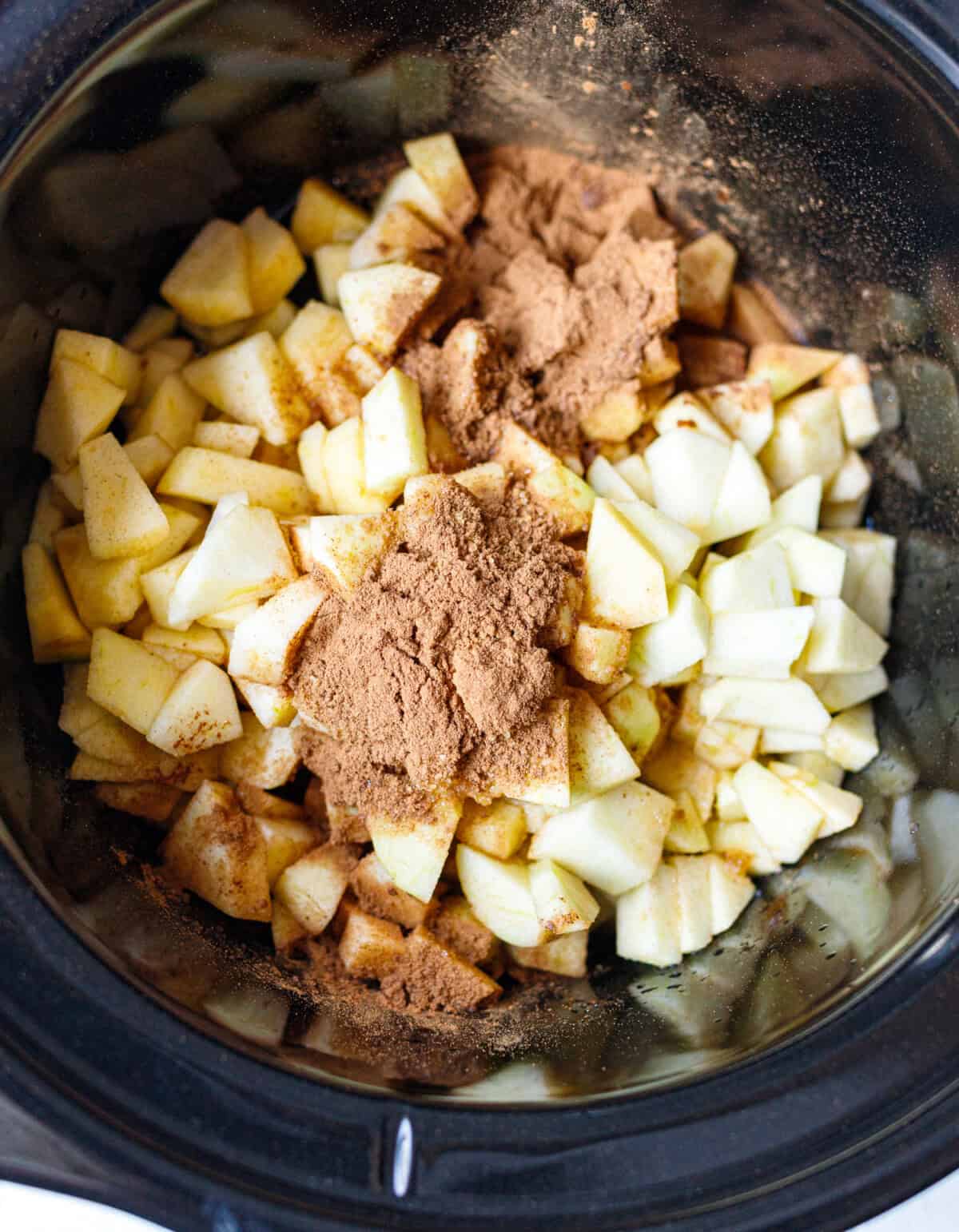 Chopped apples with cinnamon and brown sugar in a slow cooker