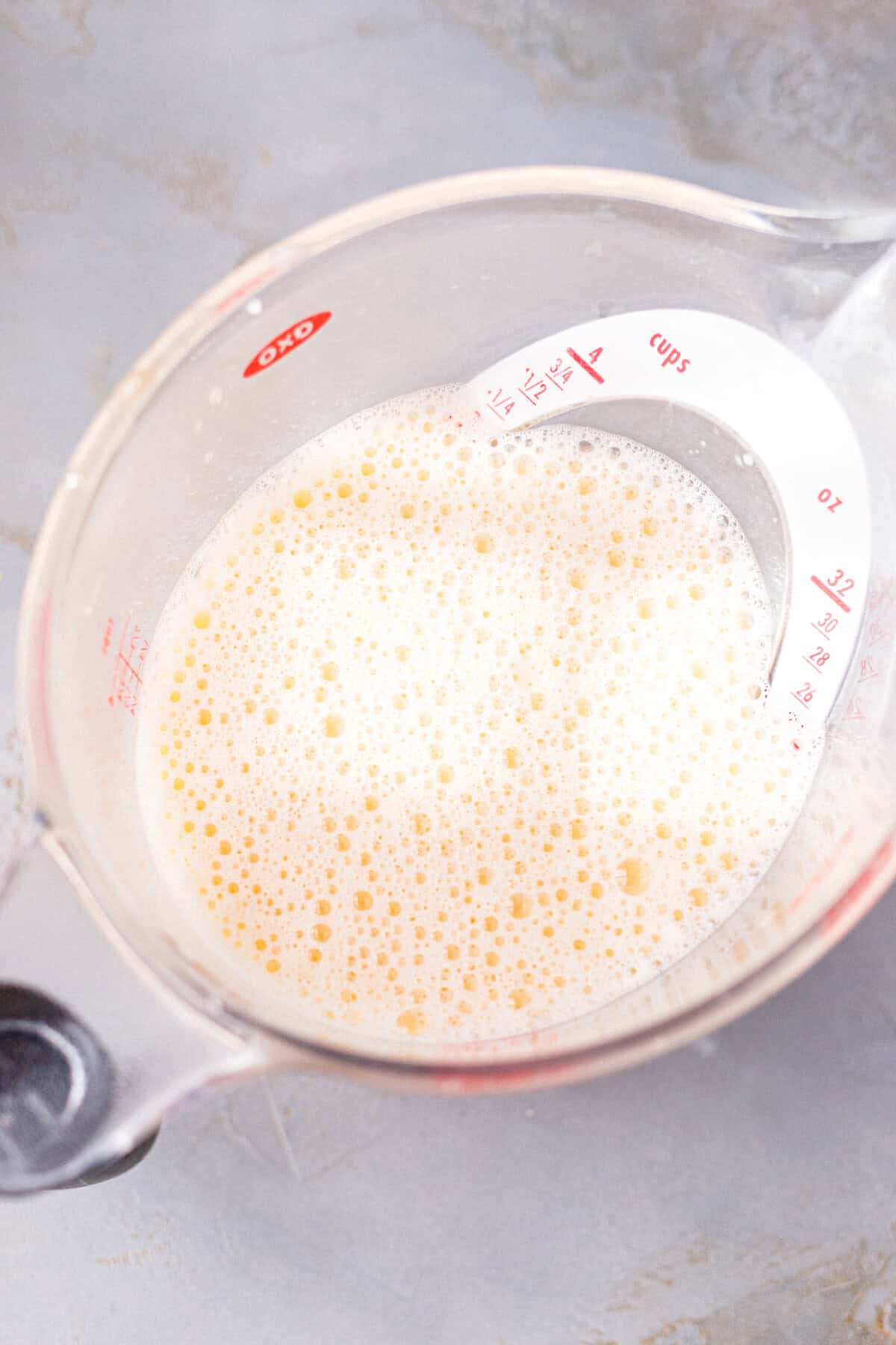 Whisked egg and almond milk custard mixture in a large glass measuring cup.