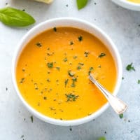 Fresh Tomato Basil Soup in a white ceramic bowl, bold color, topped with fresh basil.