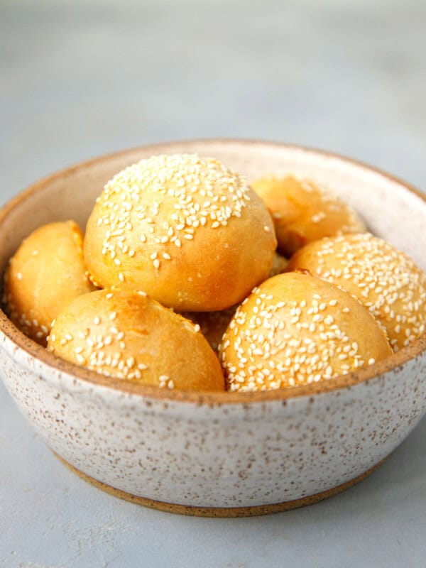 Sesame bread rolls in a speckled bowl