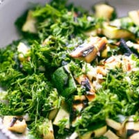 A salad bowl with grilled zucchini, cut lengthwise, topped with fresh chopped dill, parsley, garlic, olive oil, balsamic and apple cider vinegar. Bulgarian zucchini salad.