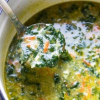A pot (Dutch oven) full of fresh and delicious Bulgarian spinach egg drop soup. Ladle full of spinach soup with curdles egg whites.