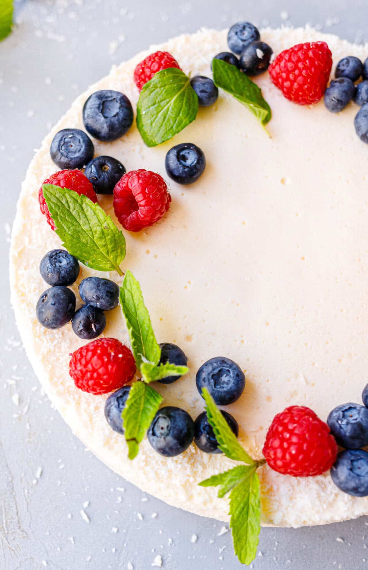 Decorating a no bake yogurt gelatin dessert with a wreath of berries and mint leaves