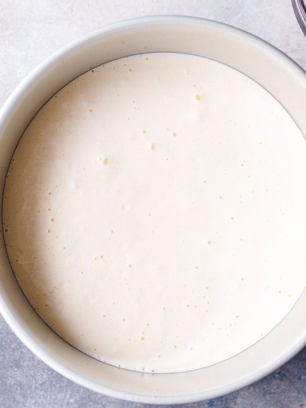 No bake yogurt cake mixture poured into a lined round pan before chilling