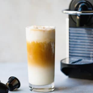 Iced Vanilla Coffee Latte Recipe Using Nespresso in a glass with coffeemaker next to it