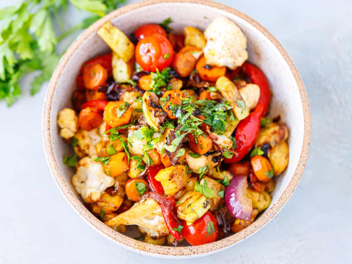 Balsamic grilled vegetables in a speckled bowl with cauliflower, red pepper, carrots and parsley