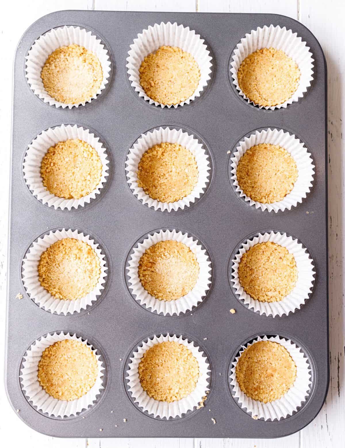 Golden cookie dough balls in paper liners on a baking tray.