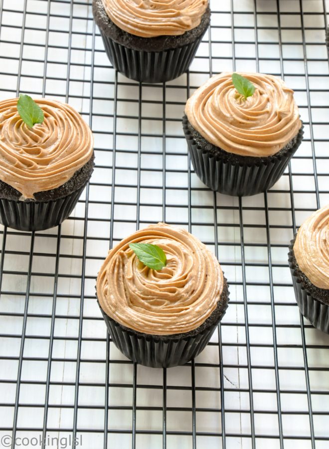Moist, crumby, rich, eggless chocolate cupcakes with Prague frosting. Made without milk, butter or eggs. On a wire rack, topped with mint.