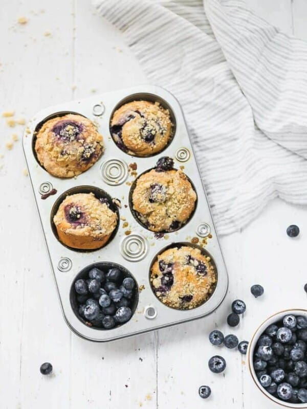 Blueberry Muffins With Olive Oil, Yogurt and Streusel Topping in a muffin tin with blueberries
