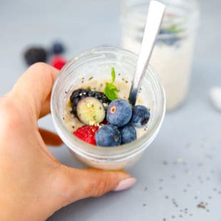A hand holding a jar with overnight oats