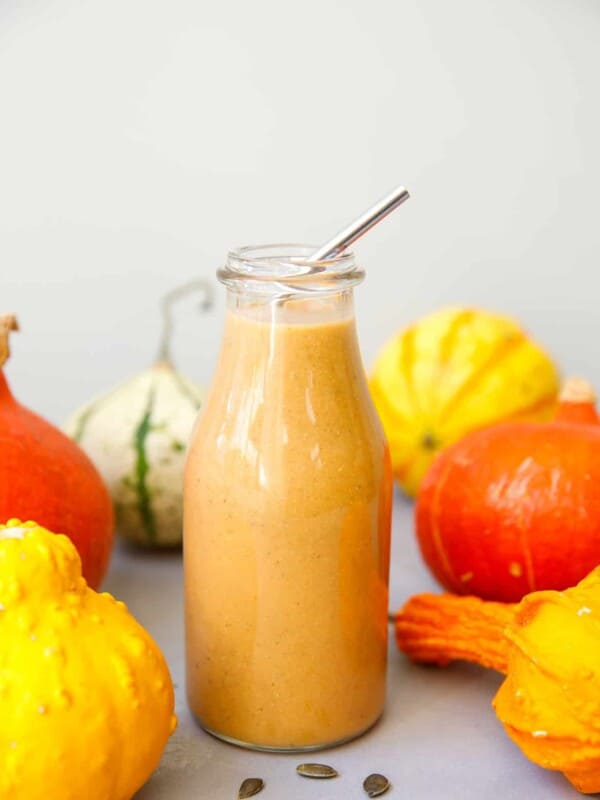 Pumpkin spice smoothie in a glass bottle with a metal straw