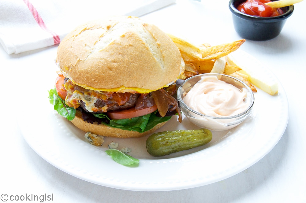 Bison Burgers With Blue Cheese, ketchup, onions, tomato, pickle and mayo, with fries on a plate