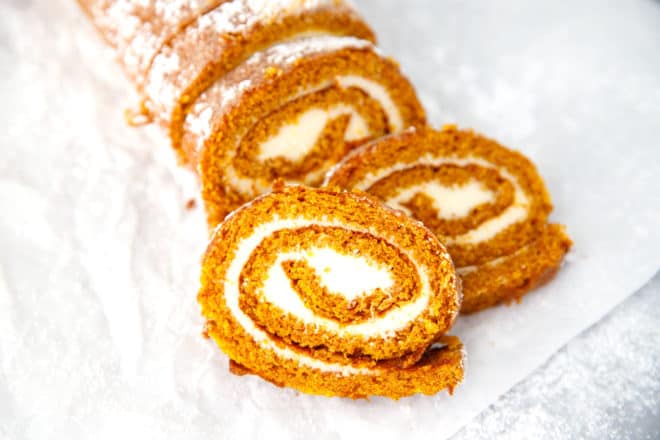 Pumpkin cake roll cut into slices on parchment paper