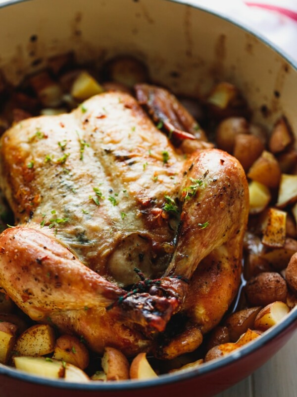 Whole roasted chicken with potatoes with golden skin in a baking dish