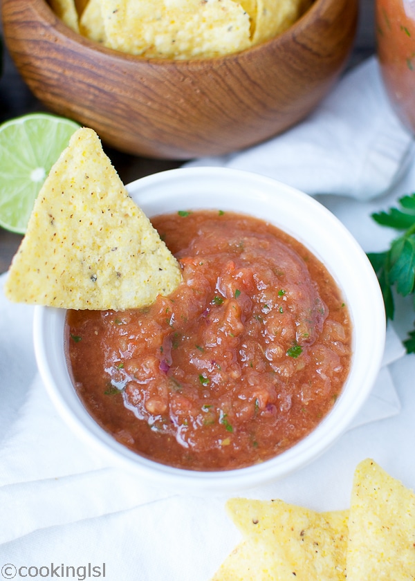 easy blender salsa for game night, in a small ramekin with chips on the side.
