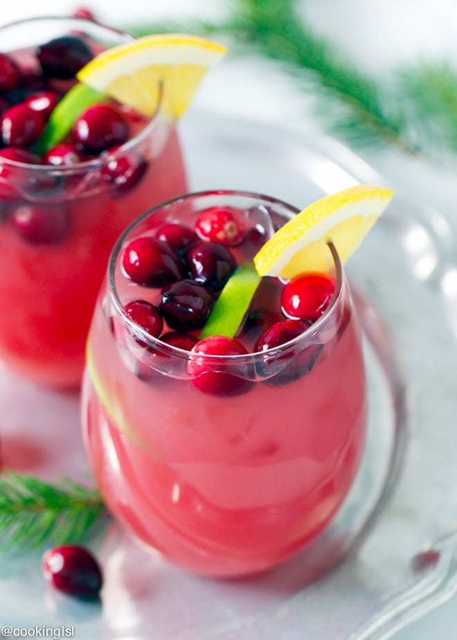 Cranberry Orange Punch in a clear glasses, topped with lime slices and cranberries. On a metal tray. Holiday favorite.