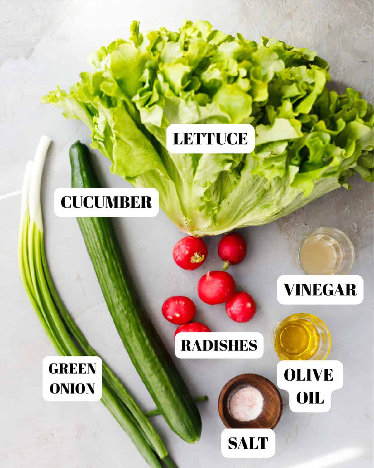 Ingredients for Bulgarian green salad including lettuce, cucumber, radishes, green onions, vinegar, olive oil and salt