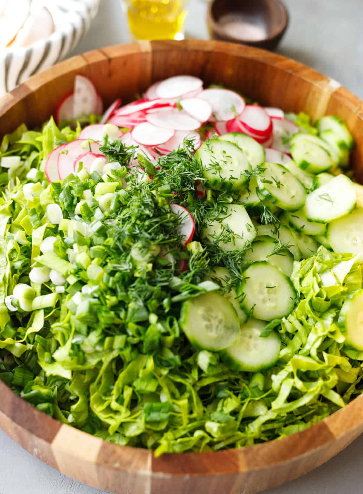 Bulgarian green salad with chopped lettuce, cucumbers, radishes, green onions and fresh dill before mixing