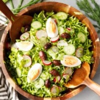 Bulgarian green salad with lettuce, cucumbers, radishes, eggs and olives served in a wooden bowl