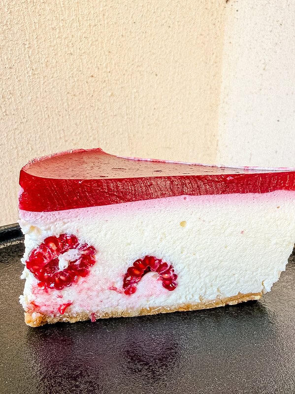 Top view of a raspberry mousse cake slice showing the smooth red jelly top
