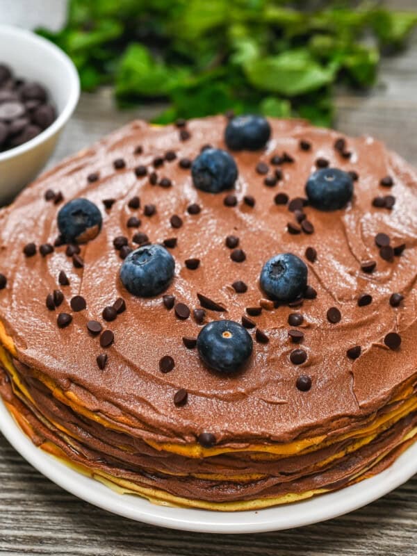 Crepe cake topped with berries on a plate