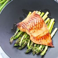 Miso salmon with asparagus on a black plate