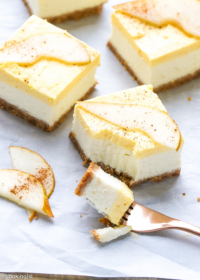 Pear mousse cheesecake pars on a white parchment paper with bite taken into one of them.