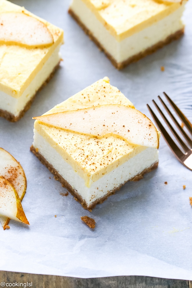 Pear mousse cheesecake bars on parchment paper with a pear slice on top