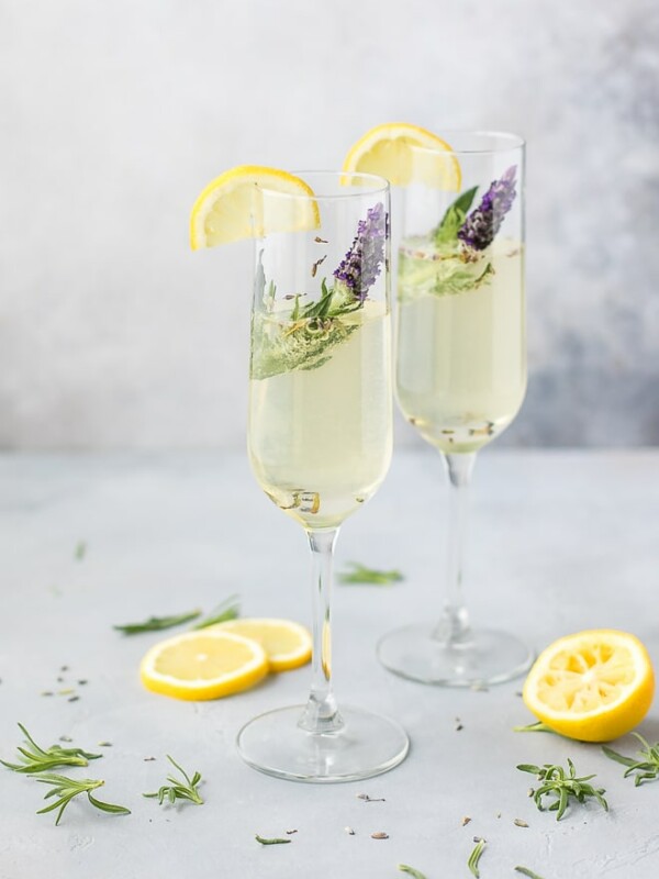 Sparkling summer poolside fresh Lavender Cocktail. Sparkling lavender cocktail with prosecco in flute glasses with fresh lavender spring and lemon slice