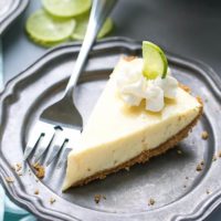 Easy way to lighten up Key Lime Pie Recipe. Made with Greek Yogurt, lime curd, homemade graham cracker crust. Flavorful summer dessert. Perfect slice of key lime pie on a plate with a fork.