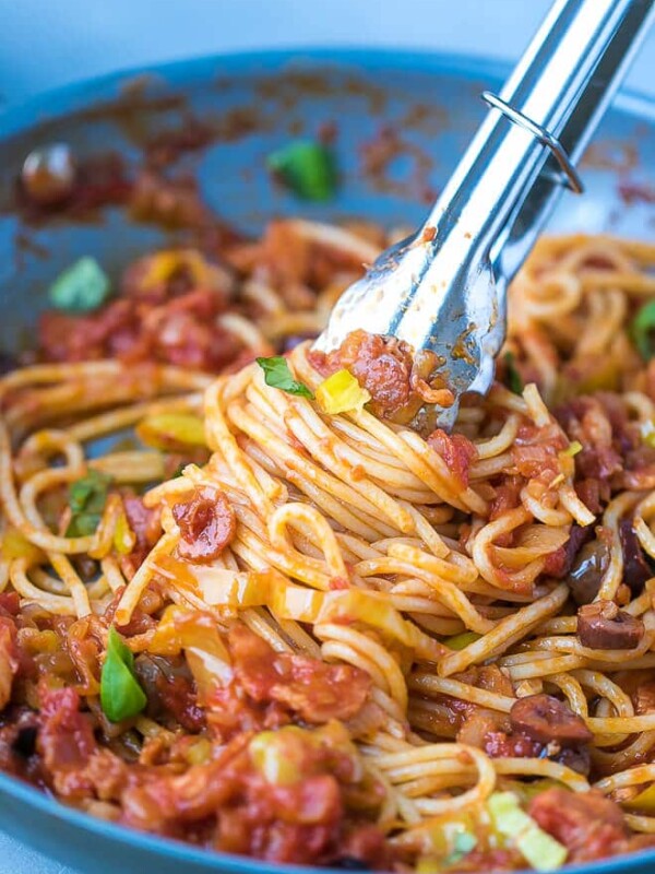 A pan with spaghetti with tomato pepperoncini peppers sauce and bacon. Thongs with spaghetti