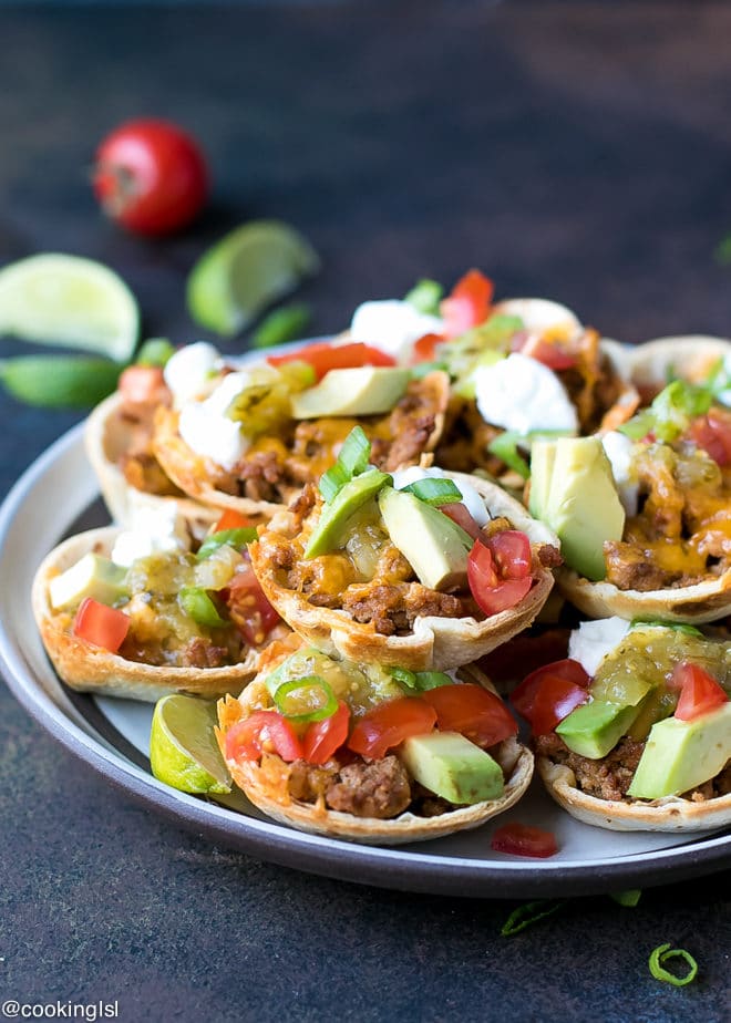 Crunchy Taco Cups With Tortillas, turkey and salsa verde recipe. Made with Pace® Salsa and perfect for a game day appetizer. A plate with mini taco appetizer, topped with avocado, sour cream and tomatoes. Lime wedges on the side. Ready in 30 minutes.