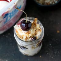 Cherry Sundae Recipe - step by step photos. Mason Jar with crushed cookies, Blue Bunny® Cherrific Cheesecake Ice cream, fresh cherries, toasted coconut flakes and chopped almonds. Topped with a fresh cherry on top.