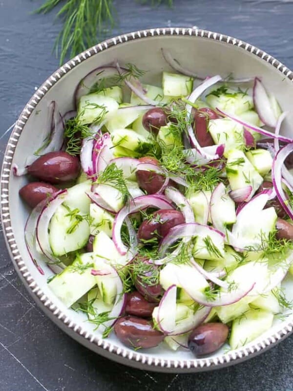A ceramic bowl with Cucumber And Onion Salad With Apple Cider Vinegar And Olives. Perfect for a light side dish or a party salad. Colorful and light.