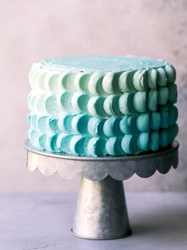 A metal cake stand with 6-inch funfetti cake, decorated with buttercream petals. Ombre smash cake for baby boy's first birthday.