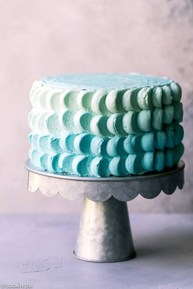 A metal cake stand with 6-inch funfetti cake, decorated with buttercream petals. Ombre smash cake for baby boy's first birthday.