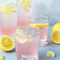 Glassed filled with pink vodka cocktail, perfect for summer parties. Pink Lemonade Vodka Cocktail Recipe-easy to make, made with KINKY Pink Liqueur. Glasses filled with ice , pink lemonade vodka and lemon slices.