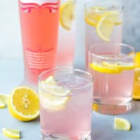 Glasses filled with light pink, gorgeous, elegant, tropical Pink Lemonade Vodka Cocktail. Summer drink, girly, easy to make.