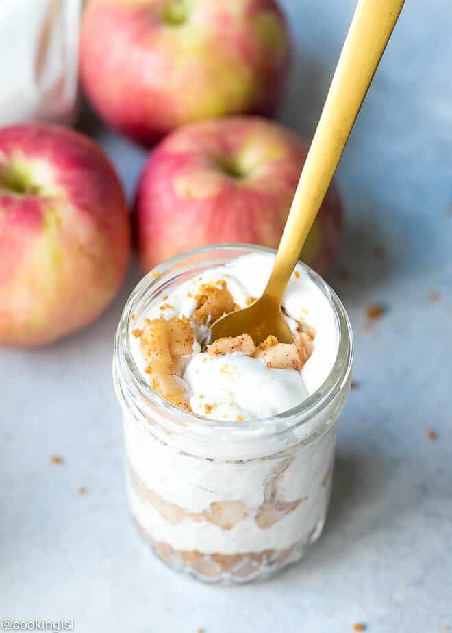 Healthy No Bake Apple Pie Cheesecake In A Jar Recipe. Small mason jars filled with healhty dessert and a gold spoon.