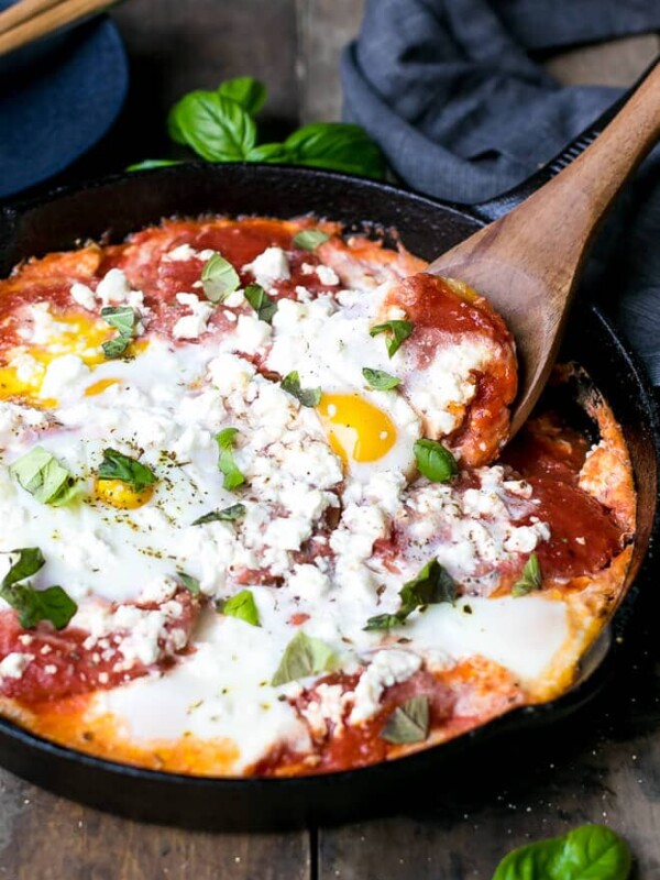 Simple ingredients and easy to make A plate with Potatoes With Tomato Sauce Feta And Eggs , runny egg yolk and delicious tomato sauce and potatoes combination. Eggs with potatoes and feta in a cast iron skillet. Cast iron skillet and wooden spoon.