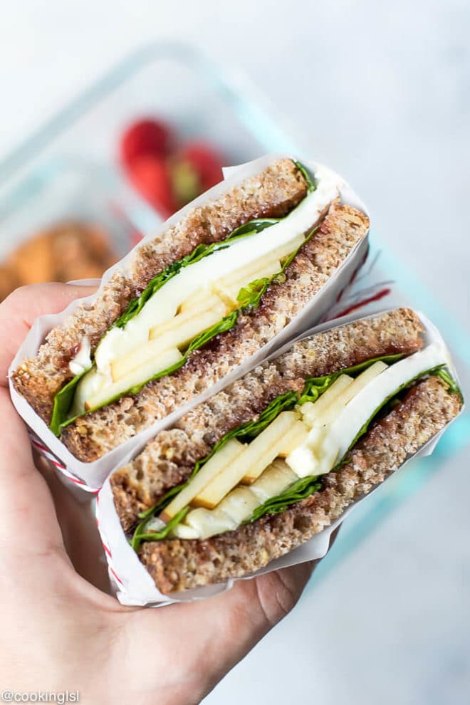Apple Spinach Goat Cheese Sandwich - Packed Lunch- two slices of whole grain bread with jam, spinach, apples and goat cheese in between. Cut in half for a healthy snack. Wrapped in parchment paper.