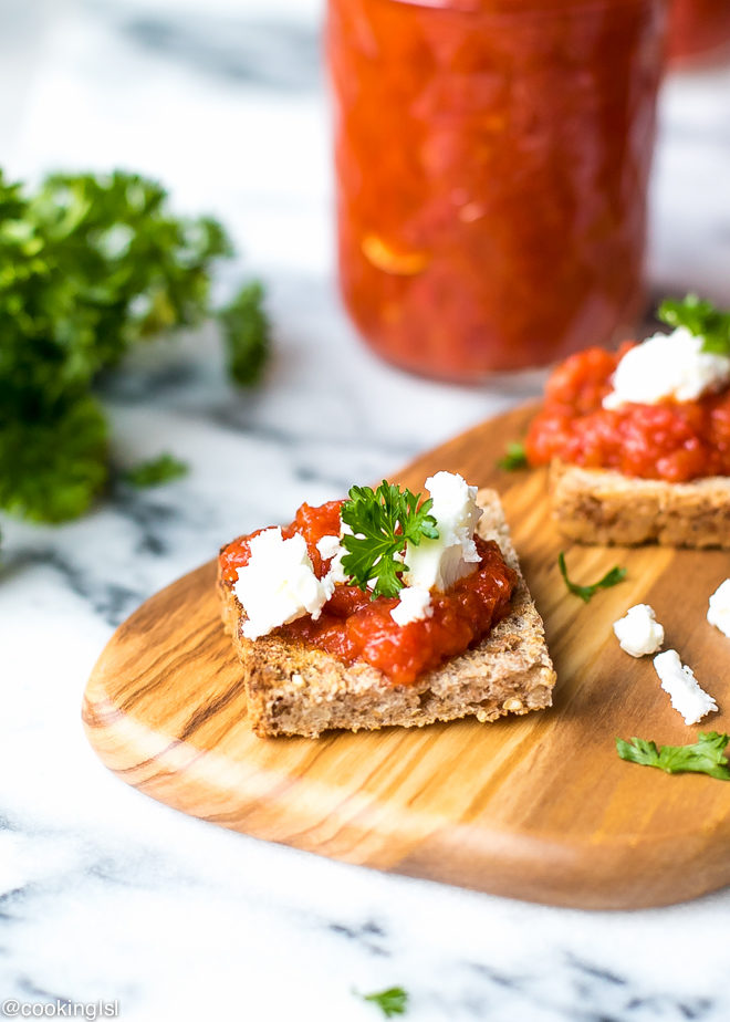 8 oz ball jars filled with red pepper tomato spread lutenitsa. Bulgarian lutenitsa recipe. Traditional Bulgarian recipe, made at home. Lutenitsa on a slice of bread, topped with feta cheese.