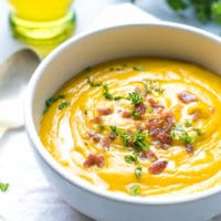 A bowl filled with creamy sweet potato soup. Made with sweet potatoes cooked in the microwave. Topped with bacon bits and parsley.